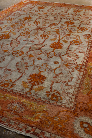 This antique Oushak rug, woven circa 1900 in Western Anatolia, showcases the region’s signature large-scale, open design with striking color contrasts. The ivory ground is adorned with an allover floral lattice rendered  ...