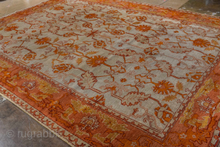This antique Oushak rug, woven circa 1900 in Western Anatolia, showcases the region’s signature large-scale, open design with striking color contrasts. The ivory ground is adorned with an allover floral lattice rendered  ...