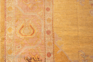 This antique Oushak rug features a luminous golden ground with soft rose undertones, creating a warm and inviting palette that is both refined and versatile. At the center, a faintly drawn medallion  ...