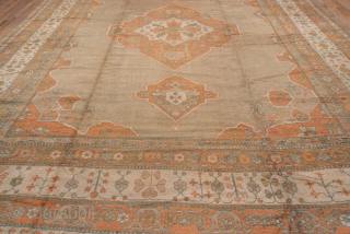 This impressive antique Oushak rug, measuring 13.5 x 17.0 feet, showcases the grandeur and artistry of late 19th to early 20th century Anatolian weaving. The rug features a bold central medallion set  ...