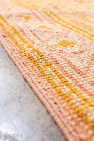 This antique Oushak rug, woven around 1900, displays the elegance and warmth for which Anatolian weavings are celebrated. The spacious field is rendered in a rare blush-rose tone, subtly shifting across the  ...