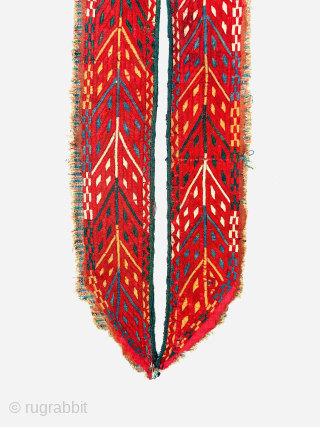 “An early 19th-century Tekke Turkmen embroidered band, featuring intricate abstract motifs in shades of red, blue, yellow, white, dark green, and apricot yellow. This embroidery is entirely silk, stitched onto a red-brown  ...