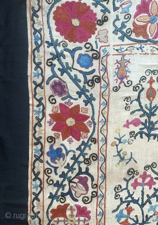 A lovely antique Uzbek silk suzani from 19th century rural Bukhara. It has fine polychrome silk chain-stitched embroidery on a cotton ground known as Karbos. The floral design is arranged in a  ...