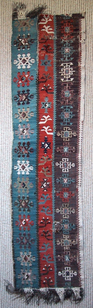 A fragment of an early Aleppo kilim. It has a beautiful palette including aubergine, coral and lilac. The white elements are woven in cotton. 107 x 27 cm, 42"x 10.5"   