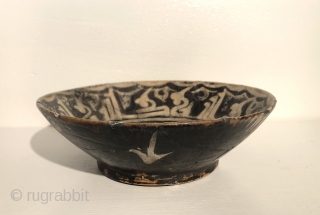 Nishapur Ceramic bowl.  North East Iran, 10th century. Size: 8 x 2.5 inches (20.5cm x 6cm) Stylized bird design in center with Kufic inscription band on rim and sparse, simple decoration  ...