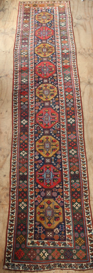 19th century Kurdish runner with a lovely abrashed emerald green border and regular repeat yellow and red medallions on a midnight blue field. New sidecords applied and minor touches of repiling. 3'2"  ...
