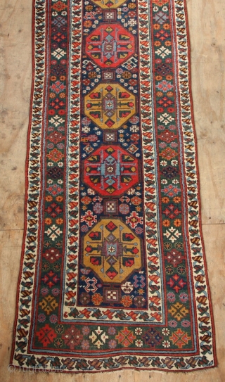 19th century Kurdish runner with a lovely abrashed emerald green border and regular repeat yellow and red medallions on a midnight blue field. New sidecords applied and minor touches of repiling. 3'2"  ...