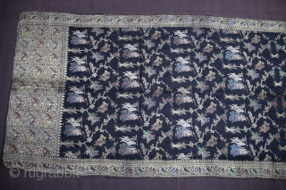 A black silk Dupatta decorated with Zari depicting birds perched on trees, tigers hunting deers, peacocks and peahens and warriors fighting on horseback and elephant back. The border, in turn, is decorated  ...