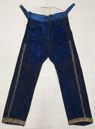 A Pair of velvet trousers in a luxurious blue colour. From Bengal.  India. Late 19th to early 20th century. The back has arrangements for suspenders with buckles made in Germany. The  ...