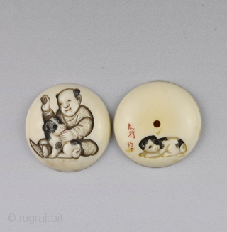 Japanese ivory manju netsuke carved in low relief  with a boy and puppy, 
the reverse is carved with another puppy end the carver's signature.
The details stained in black and red ink.
  ...