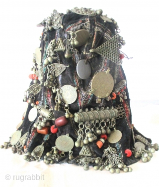 YEMENI WOMAN'S EMBELLISHED HAT upon which a multitude of coins, charms, beads of amber and coral, amulets and other superstitious and unusual items are displayed. Most rare is the use of an  ...