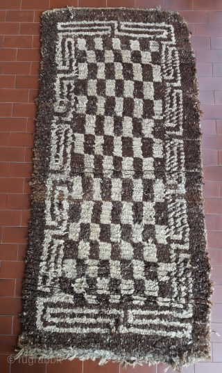 Old Tibetan Wangden rug, khaden size (circa 166 by 75 cm), born without fringes, unusual secular type with rare checkerboard pattern, natural undyed brown and white wool, “big knot” rough village weaving,  ...