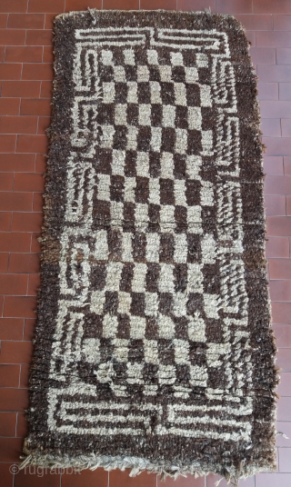Old Tibetan Wangden rug, khaden size (circa 166 by 75 cm), born without fringes, unusual secular type with rare checkerboard pattern, natural undyed brown and white wool, “big knot” rough village weaving,  ...