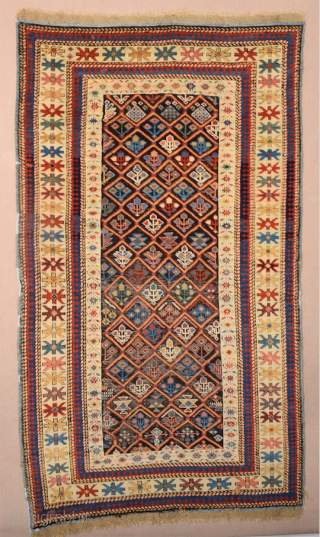 A small-format Kuba with a rare design. A repeat of flowers arranged into rows is seen in the dark brown field.19th Century Shirvan Kuba Rug The white-ground main border contains large star-shaped  ...