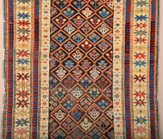 A small-format Kuba with a rare design. A repeat of flowers arranged into rows is seen in the dark brown field.19th Century Shirvan Kuba Rug The white-ground main border contains large star-shaped  ...