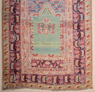 A Colorful Anatolian Prayer Ghordes prayer rug, with a steep triangular gable and a sea-green open field decorated with red carnations along the sides. A dense hyacinth pattern is seen above the  ...
