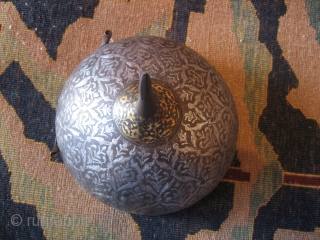 A fine Persian Safavid helmet c 1700. Heavy silver inlay with an engraved lattice pattern and floral sprays in a style seen in some "Vase" carpets. There is gold plating around the  ...