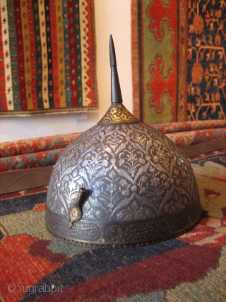 A fine Persian Safavid helmet c 1700. Heavy silver inlay with an engraved lattice pattern and floral sprays in a style seen in some "Vase" carpets. There is gold plating around the  ...