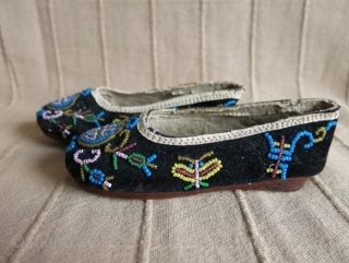 A pair of glass beaded children's shoes on velvet.                        