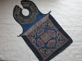 CHINESE minority child’s apron, pieced out of various natural indigo dyed canvas like cotton fabrics. Tiny transparent wires wrapped and embroidered with silk yarns. Traditional Chinese motifs. Used but still in pretty  ...