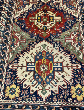 This 19th-century Caucasian Zeywa rug features a powerful geometric composition set against a deep midnight blue field. The central axis is defined by three monumental "sunburst" medallions, complemented by four halved medallions ...