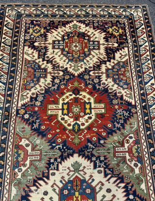 This 19th-century Caucasian Zeywa rug features a powerful geometric composition set against a deep midnight blue field. The central axis is defined by three monumental "sunburst" medallions, complemented by four halved medallions ...