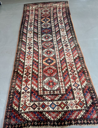 Offered here is an antique Caucasian long rug dating to the 19th century, measuring 325x125cm / 10,7ft by 4,1ft. The composition is centered around a vertical column of classic, stepped Memling guls, ...
