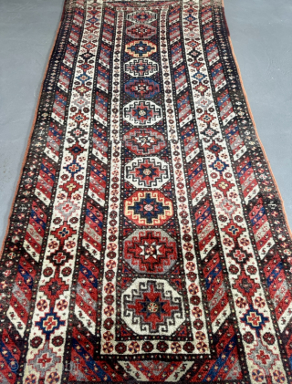 Offered here is an antique Caucasian long rug dating to the 19th century, measuring 325x125cm / 10,7ft by 4,1ft. The composition is centered around a vertical column of classic, stepped Memling guls, ...