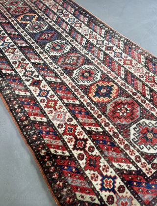 Offered here is an antique Caucasian long rug dating to the 19th century, measuring 325x125cm / 10,7ft by 4,1ft. The composition is centered around a vertical column of classic, stepped Memling guls, ...