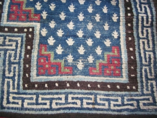 Tibetan notched saddle bottom, 24 by 51 inches; soft,floppy weave; classic design with frogs foot design on blue ground,red fretwork, and pearl border; repiling in one area in upper blue field (not  ...