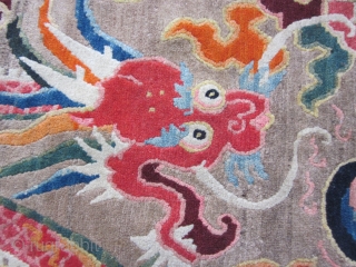 Tibetan mat, 25 by 33 inches, with vivid dragon in an array of synthetic colors. Sewn selvedge edging suggests piece may have been cut from a larger rug. 1930-40    