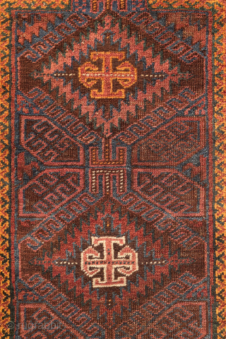 An antique Baluch prayer rug from Afghanistan, featuring an elegant, dark palette of natural dyes, including a deep indigo blue. The field contains two medallions, whose distinctive cross-shaped interior motif is echoed ...
