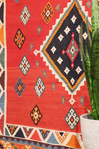 This antique Qashqai kilim is a striking example of tribal weaving, created with rich, naturally dyed colors that have retained their depth and vibrancy over time.

The main field features a bold deep-red  ...