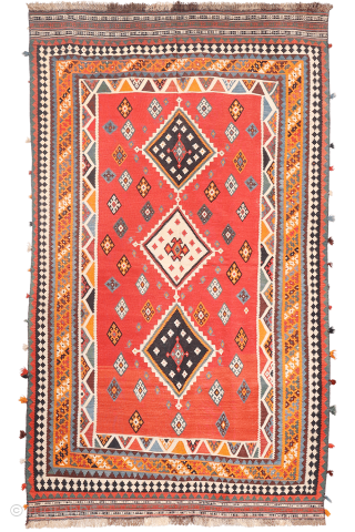 This antique Qashqai kilim is a striking example of tribal weaving, created with rich, naturally dyed colors that have retained their depth and vibrancy over time.

The main field features a bold deep-red  ...