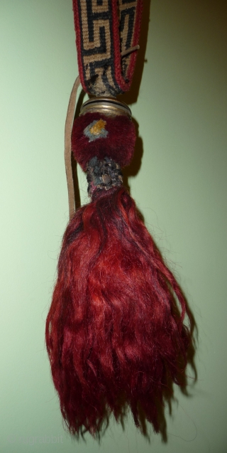 very nice tibetan animal amulet-trapping with cast bell . the band is woven in wool, the bobble under the bell is made of  red-dyed yak hair. the end is a red-dyed  ...