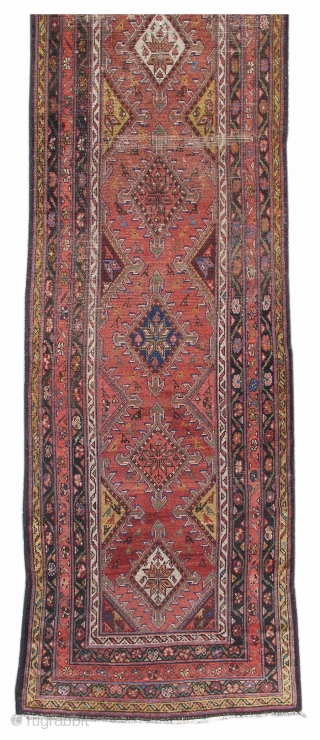 This colorful runner was woven in Persia, in the vicinity of Hamadan. A column of colorful diamonds, articulated with arrowhead motifs, is drawn against a brick red ground. Eight-pointed stars are rendered  ...