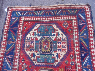 Colorful Kazak on a red ground with three medallions and several curious figures in the field.  3rd quarter of the 19th century. Size = 4'7" x 8'3". Inv. # 14692.  