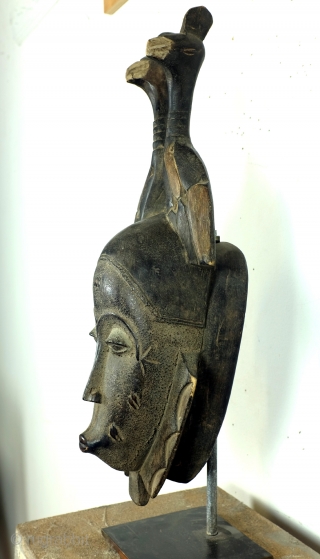 Baoulé, 
The BAOULE masks are known in African art for the smoothness of their features, protruding mouth, half closed eyes. 
The mask is topped with a headdress decorated with towering braids. 
The  ...