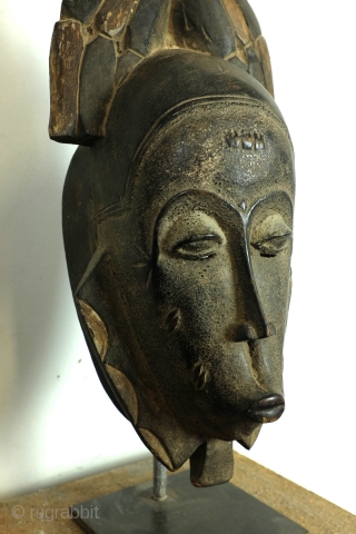 Baoulé, 
The BAOULE masks are known in African art for the smoothness of their features, protruding mouth, half closed eyes. 
The mask is topped with a headdress decorated with towering braids. 
The  ...