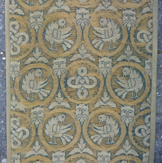 A long and narrow textile panel, 264  x 73 cm., 8’7” x 2’5”, with a repeat of circular medallions enclosing birds or endless knots is interspersed with satyr’s masks and leaves  ...