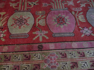 This circa 1920 Khotan #8151 handmade wool Oriental rug measures 8’1” X 5’0”. It has a depiction of four urns. Two urns are in pink, one in very pale green and one  ...