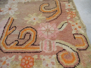This circa 1920 Khotan carpet #7064 measures 4’8” x 6’7”.  It has a pale lime green field with orange, pink and brown flowers in the center. It is a  handwoven  ...