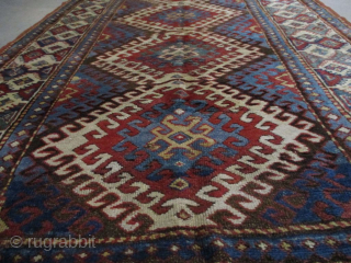 This third quarter 19th century Kazak measures 4’1” X 6’9”. It has 3 ½ diamond shaped medallions running up the field surrounded with latchhook borders in ivory. The center motif flows inward  ...