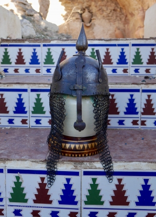 An antique Indo-Persian Helmet (Khula Khud) 19 th. century, Quajar. The front with nose shield and plume holders. Finely engraved with seated mediators and Islamic Galligraphy. length: 40 cm (with chain) diameter  ...