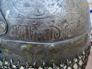 An antique Indo-Persian Helmet (Khula Khud) 19 th. century, Quajar. The front with nose shield and plume holders. Finely engraved with seated mediators and Islamic Galligraphy. length: 40 cm (with chain) diameter  ...