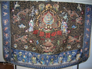 PRIEST ROBE. 
 
19th Century
The dark blue ground is elaborately worked on the front and back in satin stitch and couched gold threads showing dragons, cranes, bats, precious objects and auspicious symbols
Center  ...