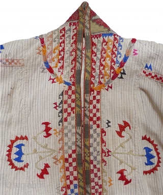 Woman's Jelak. South Uzbekistan, second quarter 20th century. Silk hand-embroidery on handwoven cotton with narrow stripes. Unlined. Silk woven and embroidered trim applied along edge; silk fringe; three pearl buttons. 35" length  ...