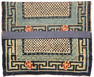 Tibetan masho (‘over-saddle’ carpet). Dark blue and white checkered center field, pearl inner border, 'rice grain' secondary border, Greek T outer border superimposed with beautiful flowers. Wool warp and weft. Circa 1920  ...