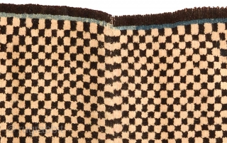 Tibetan 'butterfly-shaped' checkered makden, or under-saddle carpet. Black and white checkered center field, thin blue inner border, narrow black outer border. Circa 1920 with cotton warp and wool weft.  Size is;  ...