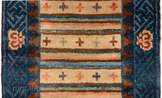 Small carpet from the Baotou region of China that, given the tigma (cross) design in the striped central field, was probably intended for Tibet. Outer border of interlocking swastikas with over-layed flowers  ...